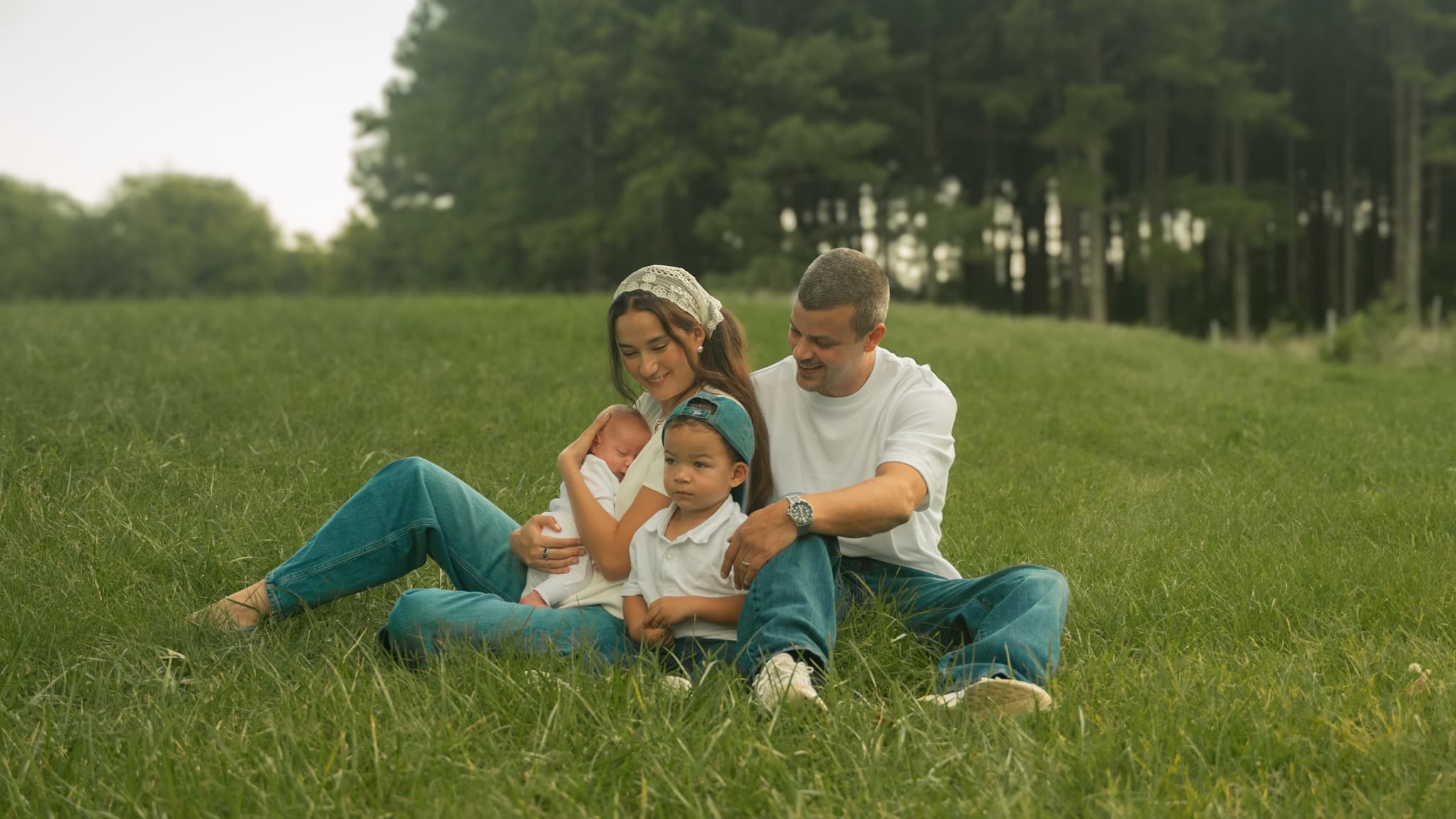 A family of four seated together in a grassy field