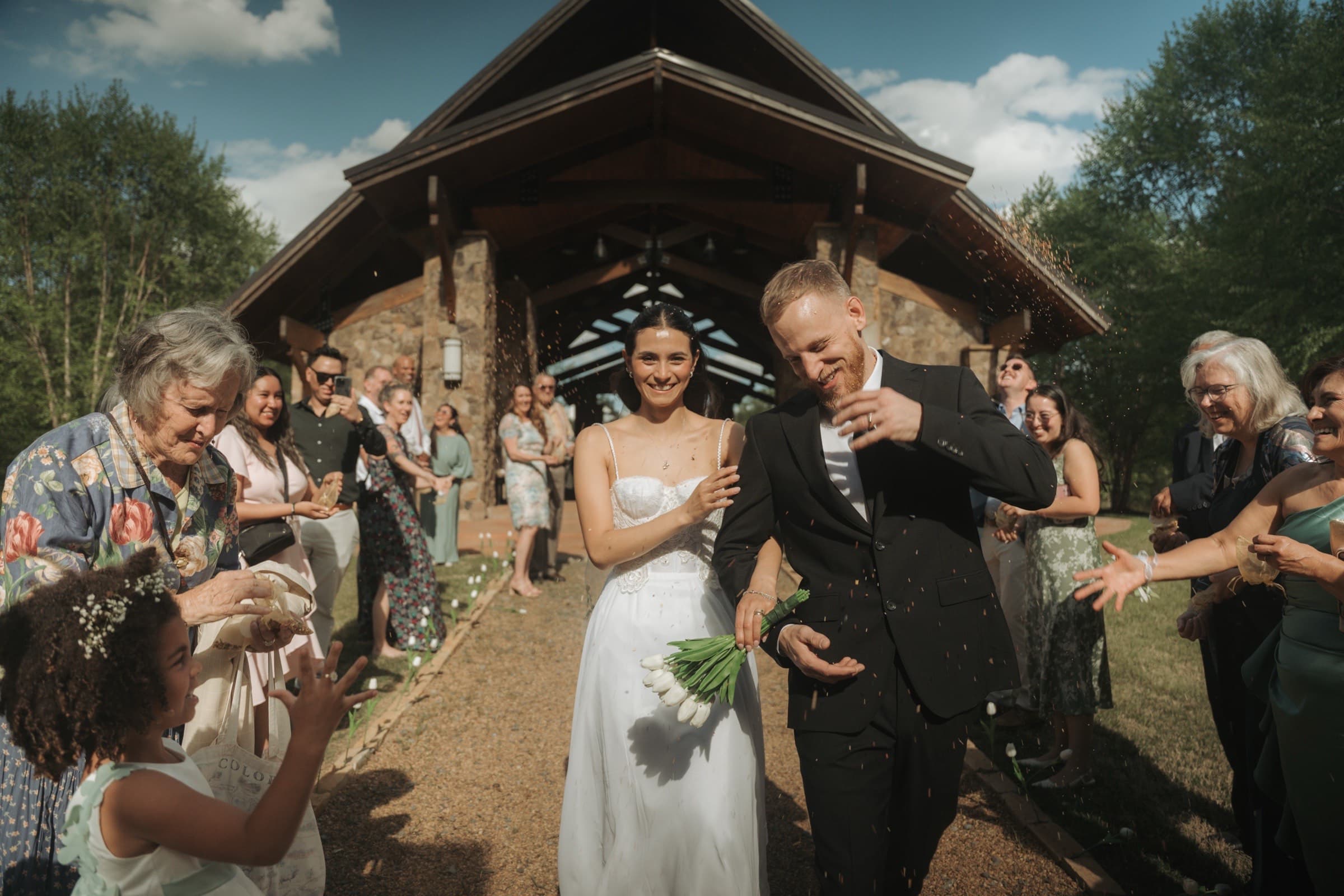 Newlyweds leaving the chapel through a scatter of petals